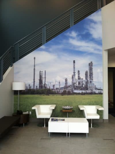 Wall mural depicting an industrial landscape with oil refinery structures under a blue sky, enhancing the immersive experience in a modern entryway.