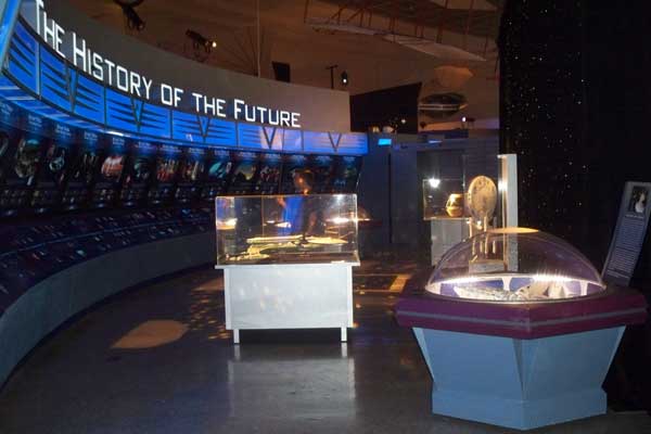 Exhibition space titled "The History of the Future" featuring illuminated displays, futuristic artifacts, and interactive installations in a trade show setting.