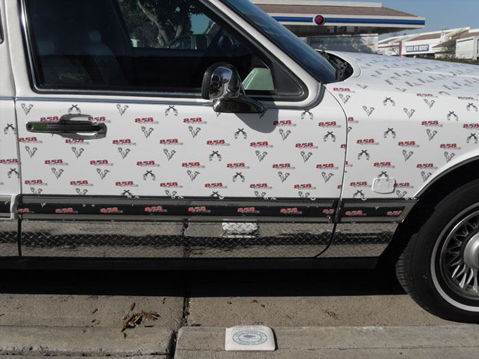 Limo wrapped with 3M Vehicle Vinyl featuring a step and repeat pattern, showcasing 858 Graphics branding, chrome accents, and a vibrant advertising design.