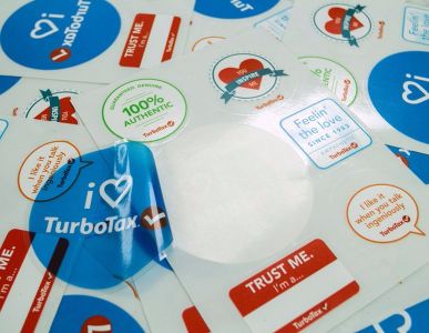various glossy stickers featuring slogans like "I ❤️ TurboTax," "100% AUTHENTIC," and "TRUST ME," showcasing vibrant colors and designs suitable for promotions and product packaging.